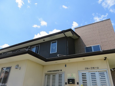 クリーム色と黒のモダンな施設外観。屋根と壁のコントラストが特徴